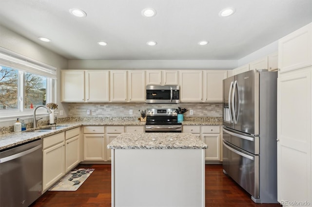 kitchen with light stone counters, appliances with stainless steel finishes, sink, and backsplash