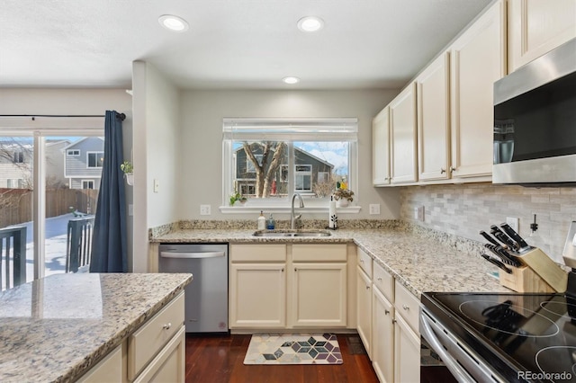 kitchen with appliances with stainless steel finishes, dark hardwood / wood-style floors, sink, backsplash, and light stone counters