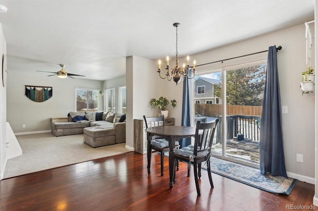 dining space with a healthy amount of sunlight, dark hardwood / wood-style flooring, and ceiling fan with notable chandelier