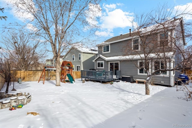 snow covered property with a playground, a deck, and a jacuzzi