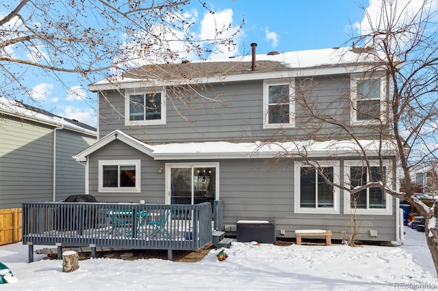 snow covered back of property featuring a deck