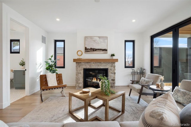 living room featuring a stone fireplace and light hardwood / wood-style floors