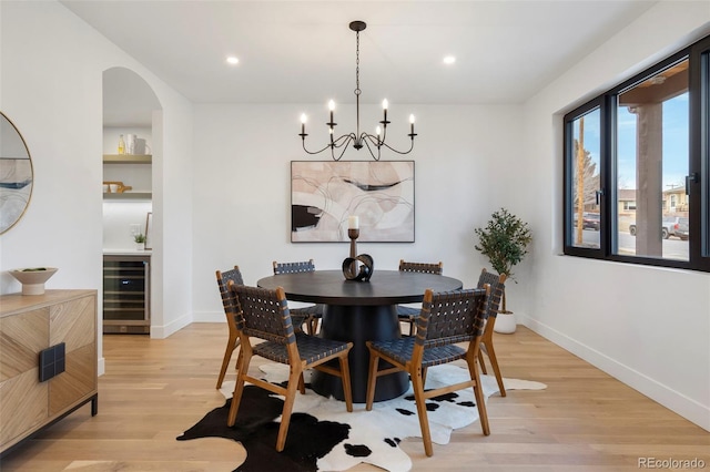 dining area with a notable chandelier, light hardwood / wood-style flooring, and beverage cooler