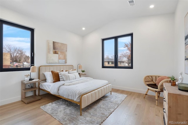 bedroom featuring multiple windows, vaulted ceiling, and light hardwood / wood-style flooring