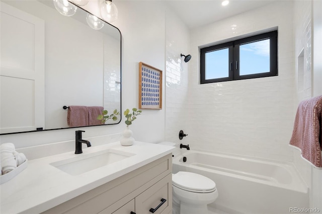 full bathroom featuring tiled shower / bath, vanity, and toilet