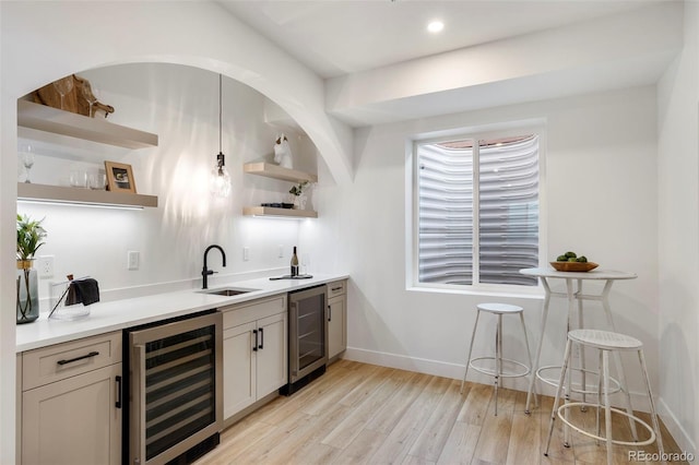 bar featuring sink, beverage cooler, and light hardwood / wood-style floors