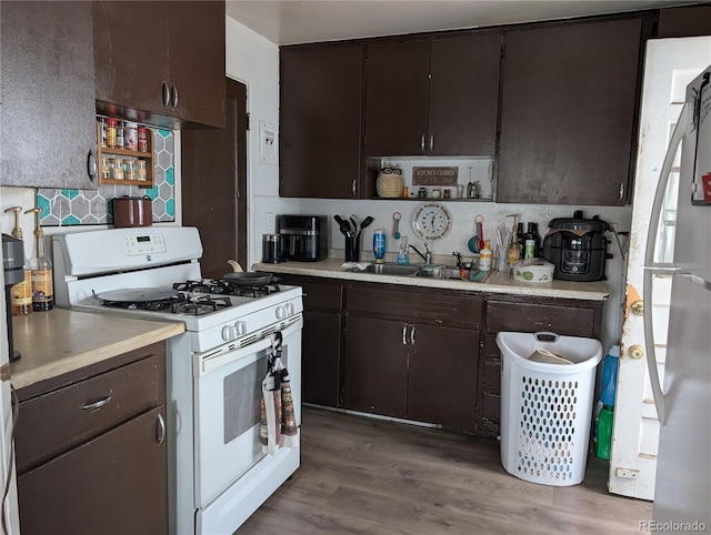 4975 Saint Paul St, Denver, CO 80216 - kitchen with white range with gas cooktop, freestanding refrigerator, light countertops, and wood finished floors