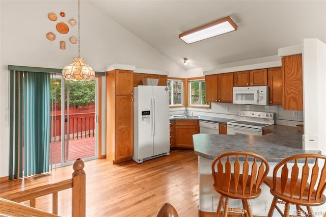 131 Morgan Ct, Loveland, CO 80537 - kitchen featuring white appliances, light wood-style flooring, a peninsula, brown cabinetry, and high vaulted ceiling