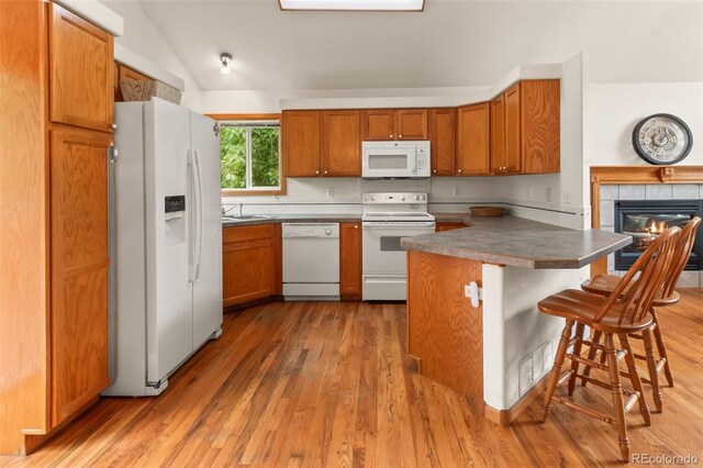 131 Morgan Ct, Loveland, CO 80537 - kitchen with white appliances, light wood-style flooring, a breakfast bar, brown cabinetry, and vaulted ceiling