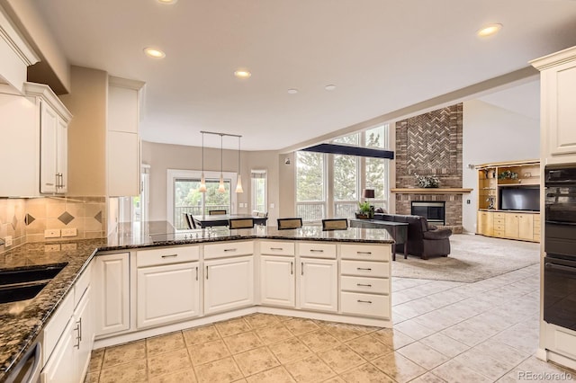 7758 Edgewater Ct, Lone Tree, CO 80124 - kitchen featuring a sink, stainless steel dishwasher, a fireplace, a peninsula, and tasteful backsplash