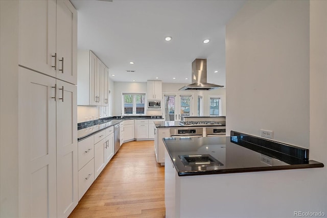 371 Birch St, Denver, CO 80220 - kitchen featuring island range hood, light wood-type flooring, a peninsula, appliances with stainless steel finishes, and white cabinetry