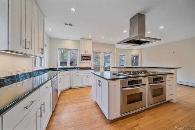 371 Birch St, Denver, CO 80220 - kitchen with dark countertops, island exhaust hood, white cabinetry, appliances with stainless steel finishes, and visible vents