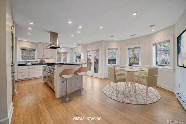 371 Birch St, Denver, CO 80220 - kitchen with white cabinets, light wood-style flooring, dark countertops, baseboards, and island range hood