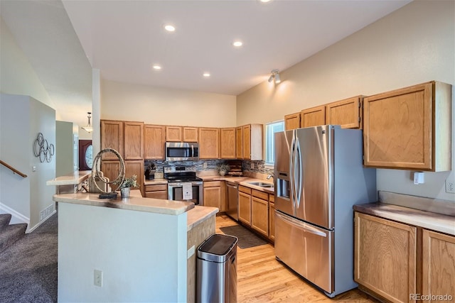 kitchen featuring a center island with sink, decorative backsplash, a towering ceiling, sink, and stainless steel appliances