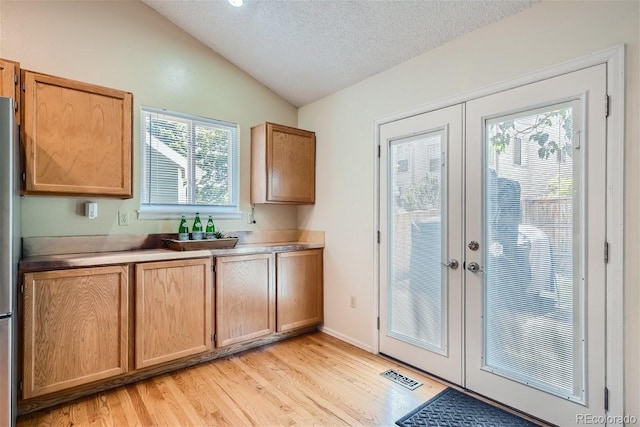 doorway with lofted ceiling, french doors, a wealth of natural light, and a textured ceiling