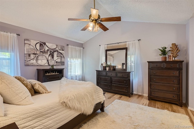 bedroom featuring ceiling fan, vaulted ceiling, multiple windows, and light hardwood / wood-style floors