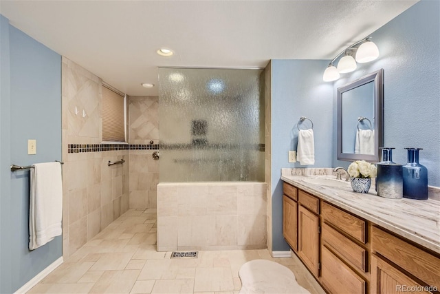 bathroom with tiled shower and vanity