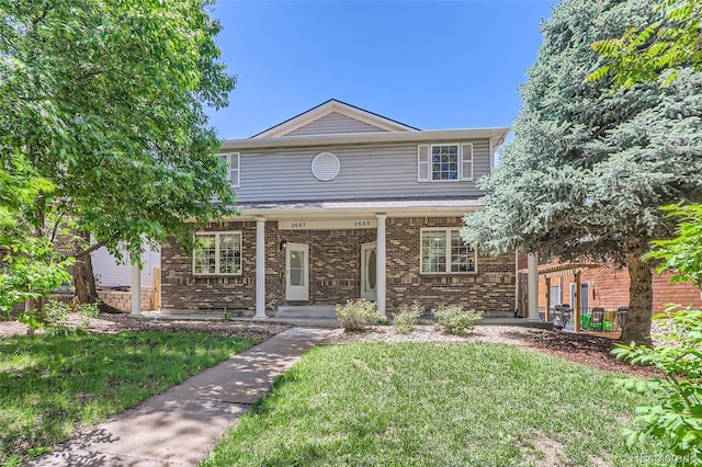 traditional home with covered porch, brick siding, and a front lawn