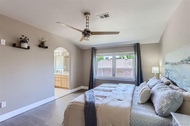 bedroom featuring arched walkways, light wood-style flooring, a ceiling fan, visible vents, and baseboards