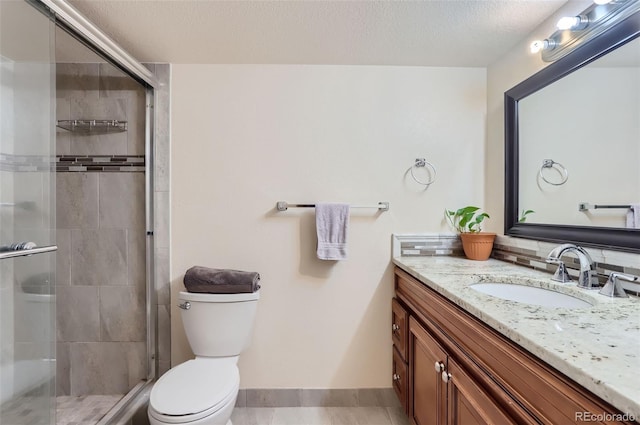 bathroom with toilet, a textured ceiling, a shower stall, and vanity