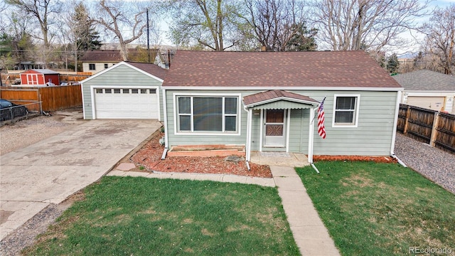 view of front of home with a shingled roof, a front yard, a detached garage, and fence