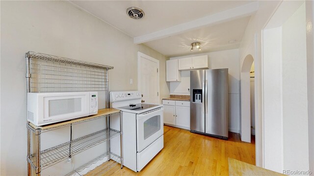 kitchen with white appliances, visible vents, white cabinets, and arched walkways