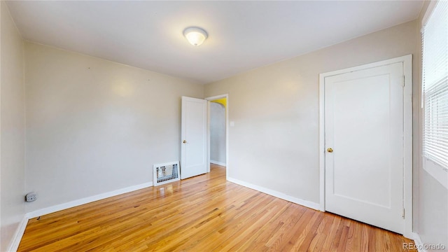 unfurnished bedroom with baseboards, heating unit, and light wood-type flooring