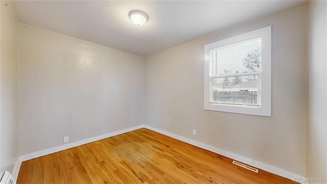 spare room with baseboards, visible vents, wood finished floors, and baseboard heating