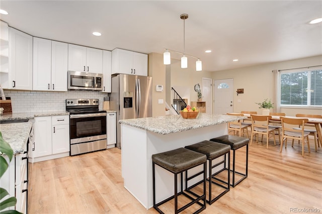 10527 Pierson Cir, Westminster, CO 80021 - kitchen featuring appliances with stainless steel finishes, light wood-type flooring, white cabinetry, and recessed lighting