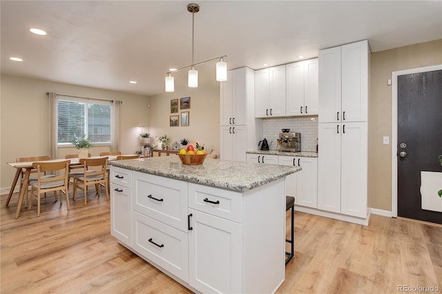 10527 Pierson Cir, Westminster, CO 80021 - kitchen with backsplash, light wood-type flooring, a kitchen island, recessed lighting, and white cabinets