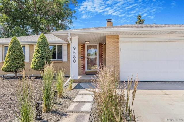 9580 W 51st Ave, Arvada, CO 80002 - ranch-style house featuring concrete driveway, a chimney, brick siding, an attached garage, and a shingled roof