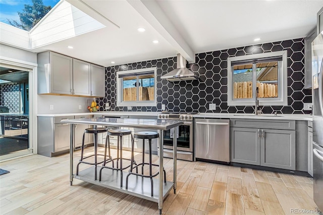 9580 W 51st Ave, Arvada, CO 80002 - kitchen featuring appliances with stainless steel finishes, gray cabinets, island exhaust hood, light wood-style flooring, and beam ceiling
