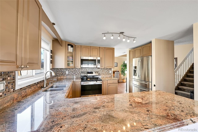 kitchen with decorative backsplash, appliances with stainless steel finishes, light stone countertops, and a sink