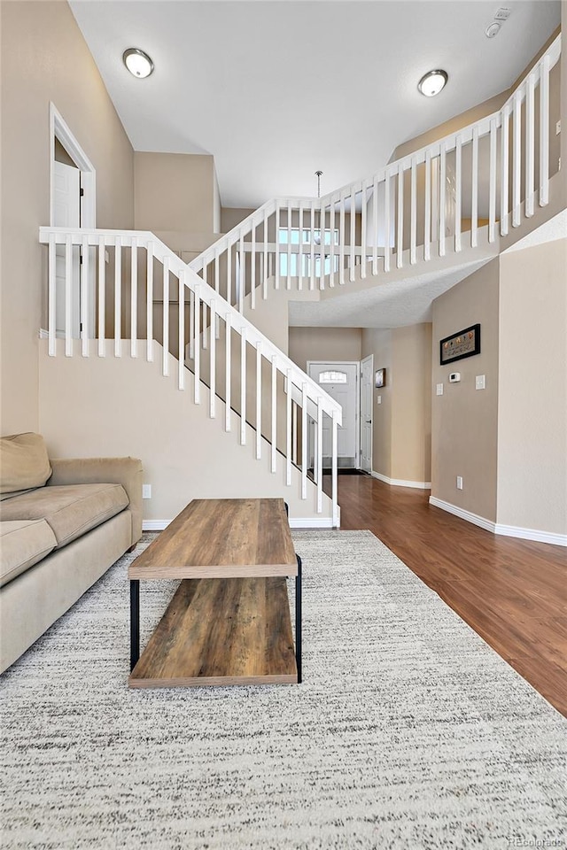 living room featuring baseboards, wood finished floors, and stairs