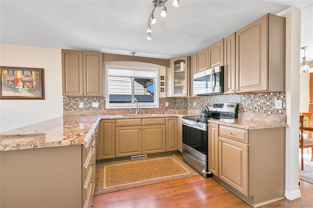 kitchen with visible vents, a sink, stainless steel appliances, a peninsula, and light wood finished floors