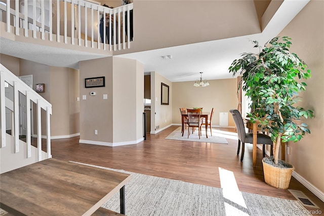 living area featuring a chandelier, visible vents, baseboards, and wood finished floors