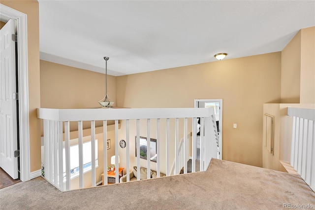 hallway with carpet flooring and an upstairs landing