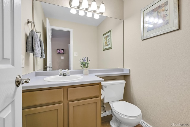 half bathroom featuring toilet, vanity, and baseboards