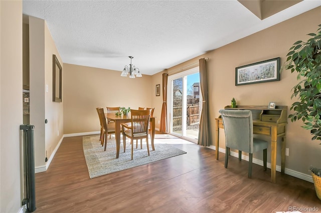 dining area featuring a notable chandelier, wood finished floors, baseboards, and a textured ceiling