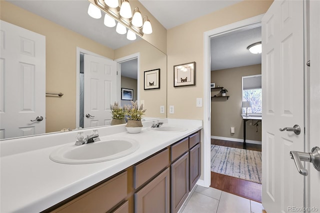 bathroom featuring a sink, baseboards, double vanity, and tile patterned flooring