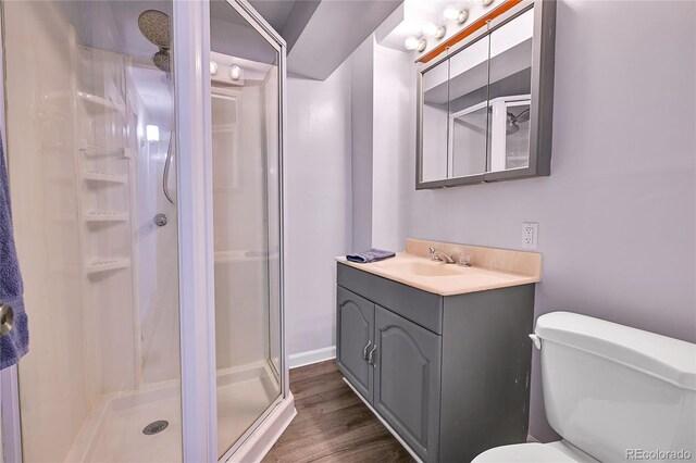 bathroom with toilet, a stall shower, vanity, and wood finished floors