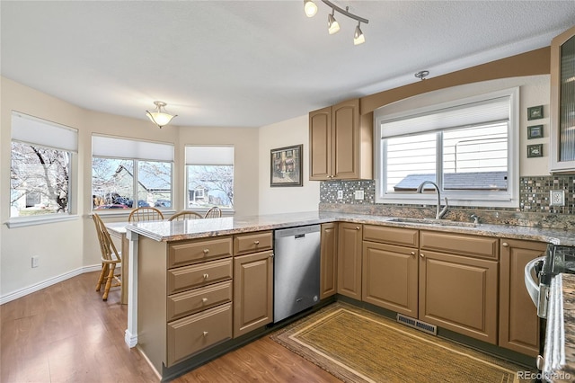 kitchen with a sink, dishwasher, a peninsula, wood finished floors, and range