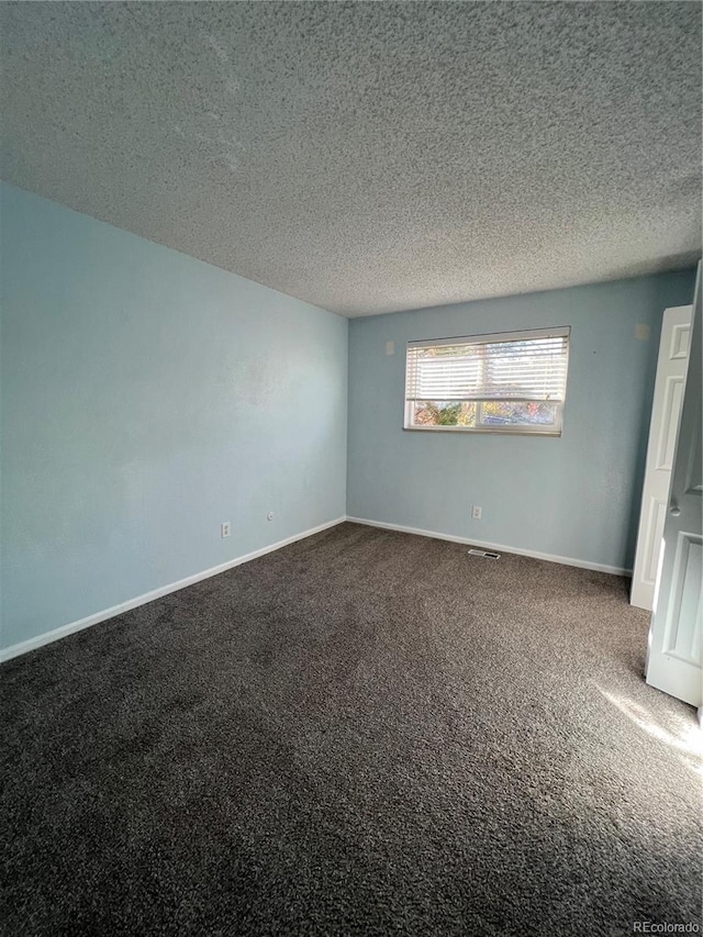 empty room with carpet and a textured ceiling