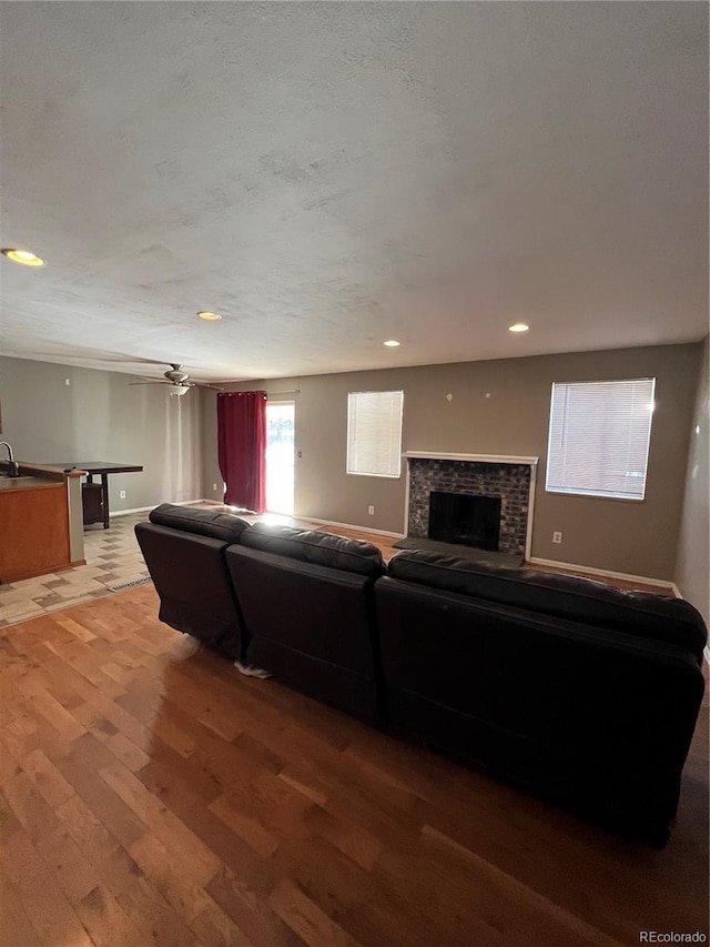 living room featuring hardwood / wood-style flooring, ceiling fan, and a textured ceiling