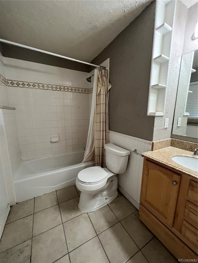 full bathroom with tile patterned floors, vanity, a textured ceiling, shower / tub combo with curtain, and toilet