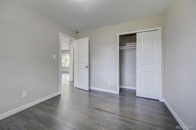 unfurnished bedroom featuring dark wood-type flooring, a closet, and a textured ceiling