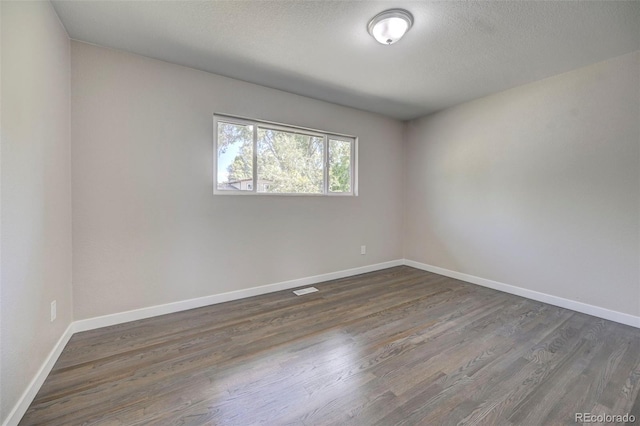 spare room featuring dark hardwood / wood-style floors and a textured ceiling