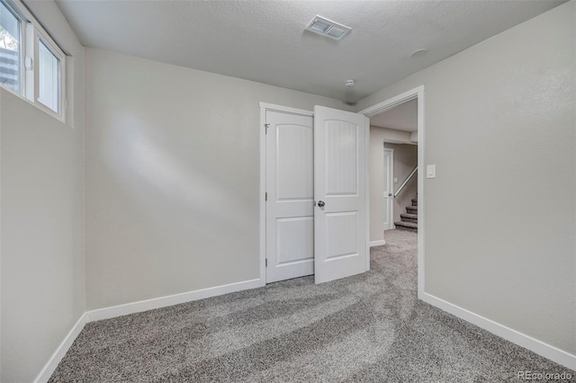 unfurnished bedroom featuring a textured ceiling and carpet flooring