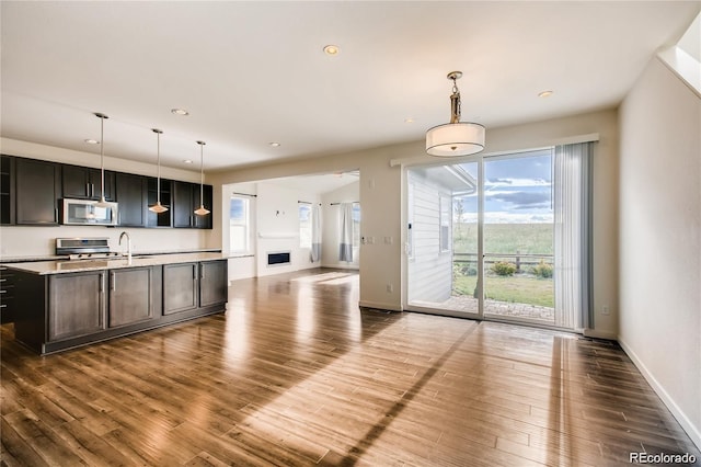 kitchen featuring a center island with sink, appliances with stainless steel finishes, dark hardwood / wood-style floors, and decorative light fixtures