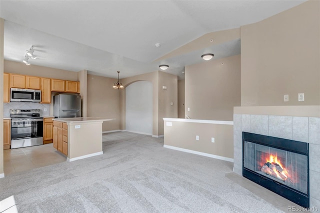 9387 Ashbury Cir Unit 203, Parker, CO 80134 - kitchen featuring stainless steel appliances, open floor plan, a kitchen island, a fireplace, and light brown cabinetry